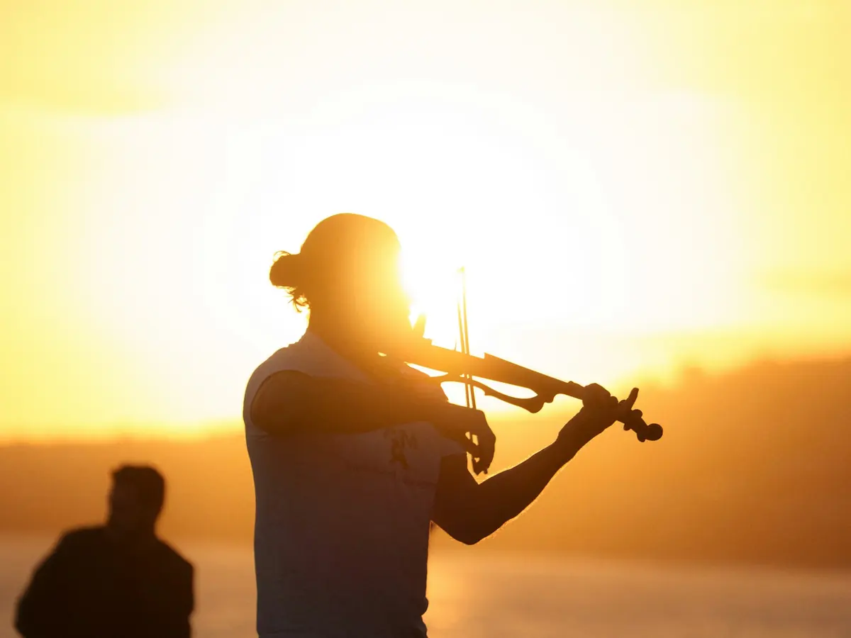 Violinist playing a romantic serenade at sunset by the sea