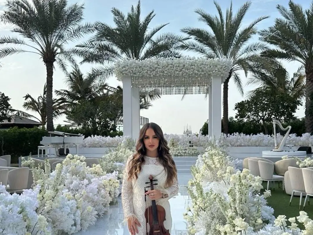 Wedding violinist walking down a floral aisle at an outdoor wedding in Dubai